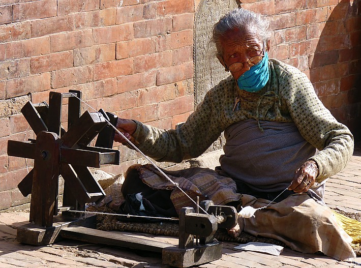 Old Nepalese woman with spinning wheel in Patan
